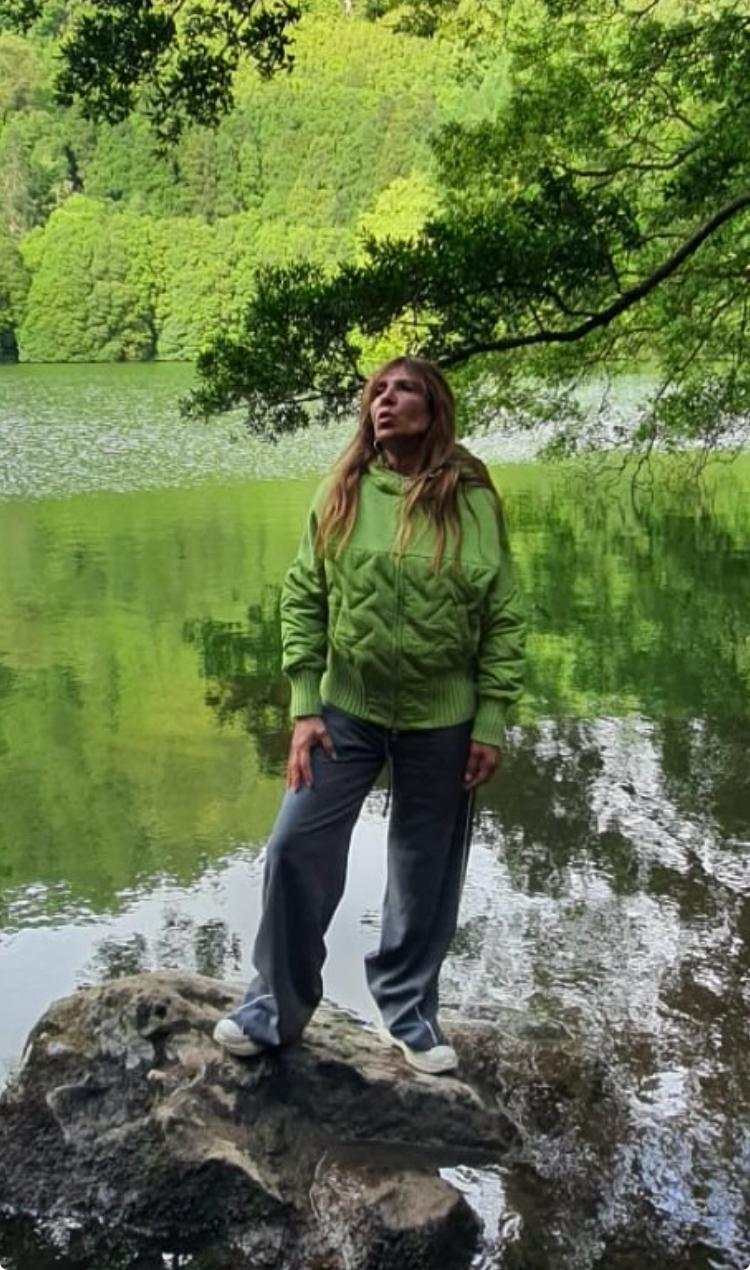 Ana Sofia Cid sobre uma rocha num lago dos Açores, rodeada de natureza verde