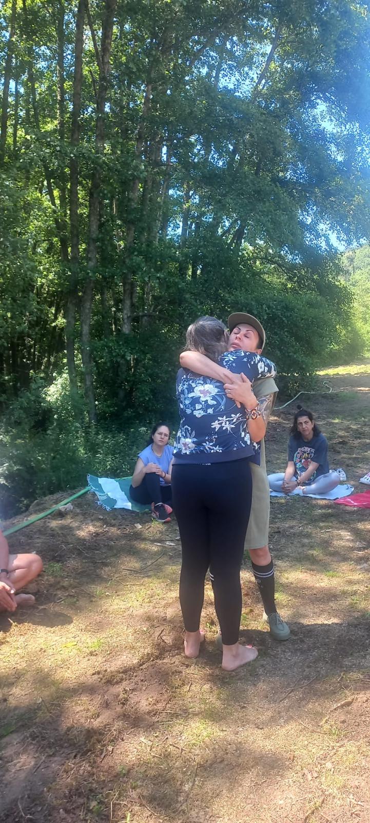 Abraço sustentado entre participantes de retiro na floresta