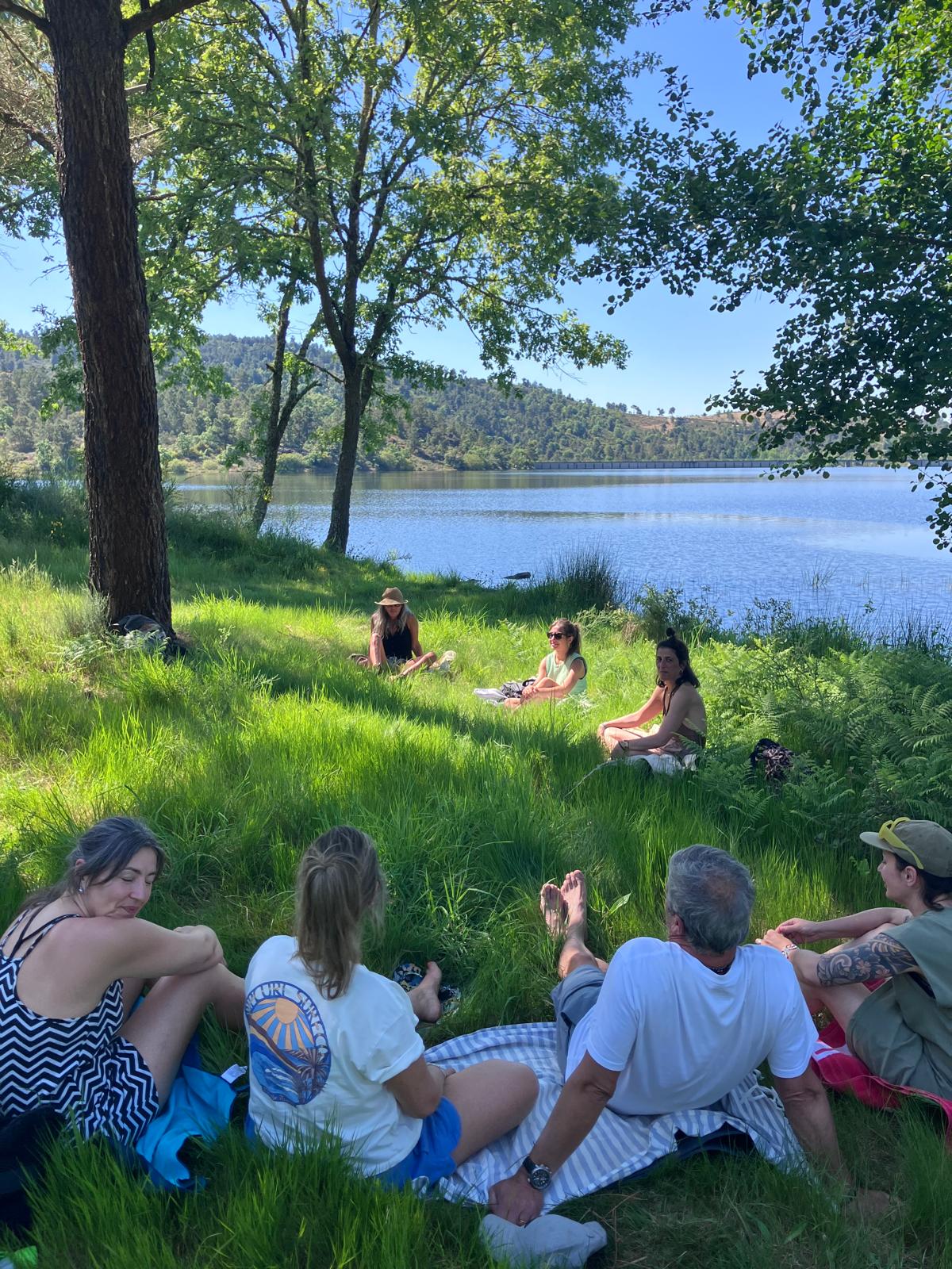 Grupo em meditação à beira do lago, sob as árvores