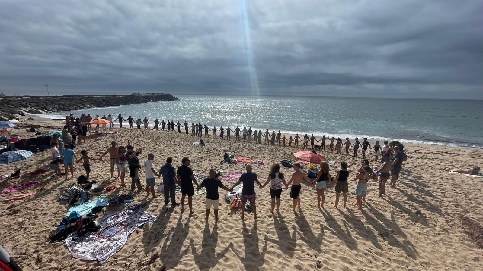 Grande círculo de mãos dadas na praia, ao pôr do sol