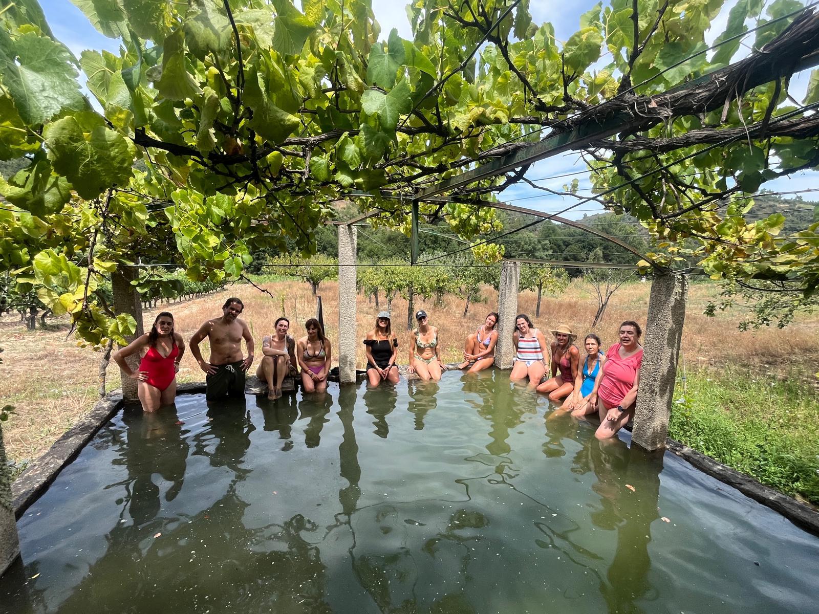 Participantes do retiro num tanque sob latada de vinhas